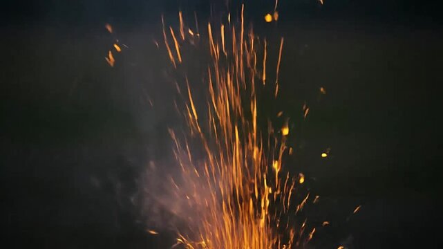 Bright orange sparks erupting from a hot fire against a dark background
