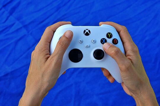 Hands holding a modern white video game controller for immersive digital entertainment, ready to engage in virtual worlds and interactive experiences