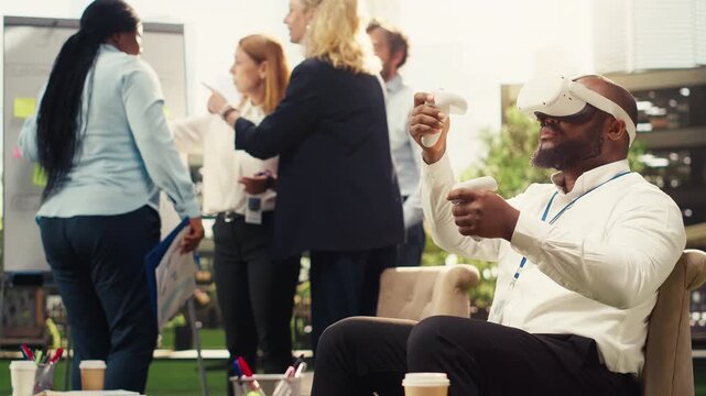 Smiling businessman with VR glasses lifting VR controllers for interactive simulation, 3D innovation of virtual reality in outdoor business park, colleagues beside vision board, for strategy planning.