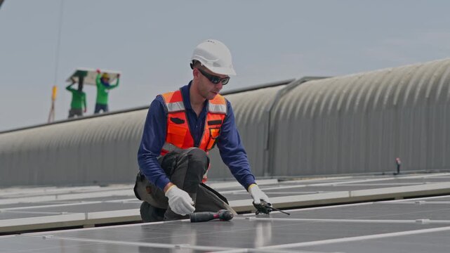 Man installing solar panels on a rooftop wearing safety equipment and using tools under clear sunny skies