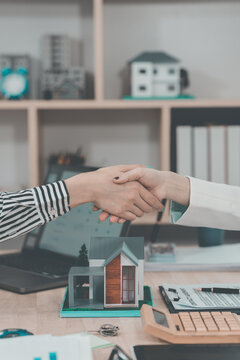 Real estate agent shaking hands with client after signing contract agreement for buying house.