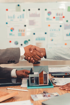 Real estate agent shaking hands with client after signing contract agreement for buying house.