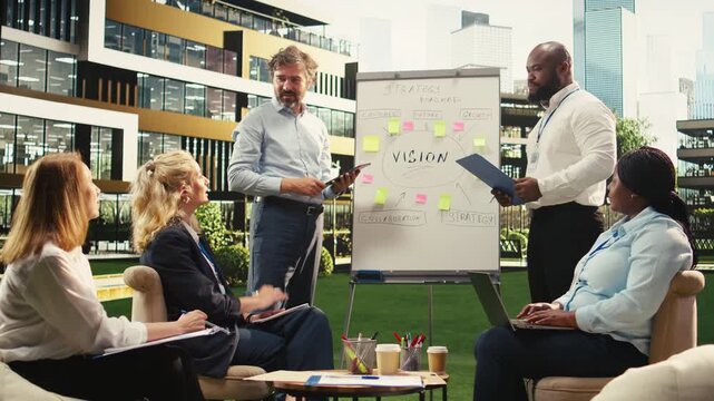 Diverse business people explaining vision implementation with sticky notes, gesturing with open hands during outdoor presentation, informal discussion.