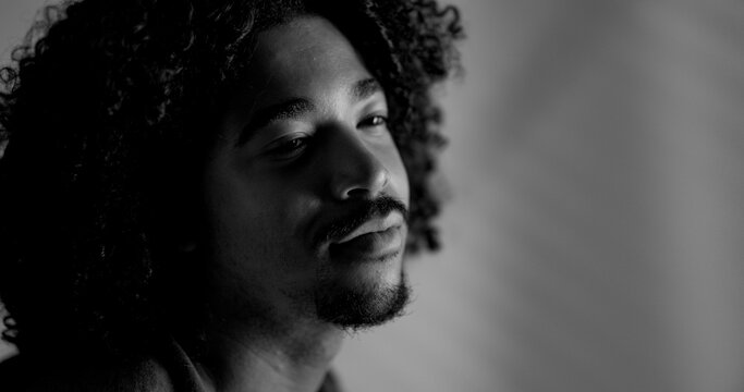 Young man with curly hair and beard looking away in a contemplative moment