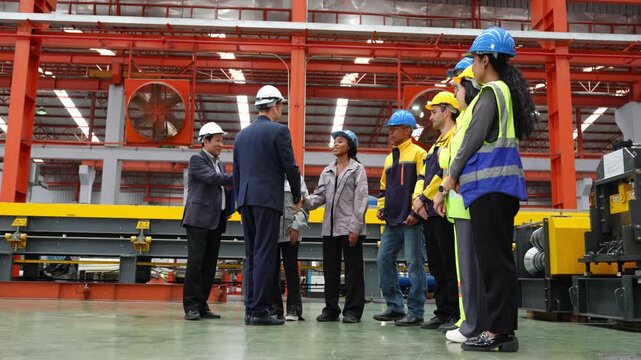 Group of workers engaged in safety meeting in industrial factory setting with equipment and machinery