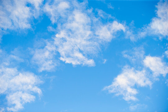 Beautiful bright blue sky with soft white fluffy clouds background.   A stunning and serene background featuring a vibrant blue sky filled with scattered, light fluffy white clouds.