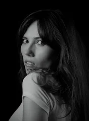Woman with long hair looking over her shoulder, isolated on black background © 4kclips