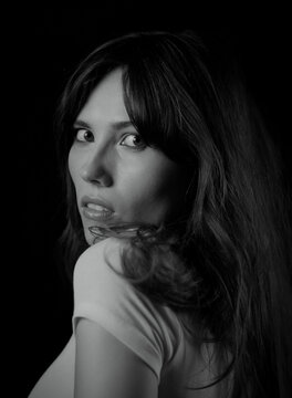 Woman with long hair looking over her shoulder, isolated on black background