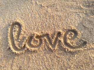 This photo features the word Love handwritten on clean beach sand. Perfect for romantic concepts, summer vacations, Valentine's Day, greeting card backdrops, or beach wedding themes. © Komang