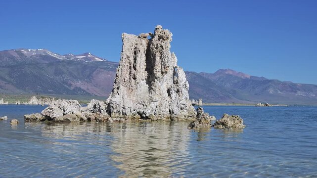 Tufa tower rises from rippling Mono Lake in front of the Eastern Sierra Mountains in summer