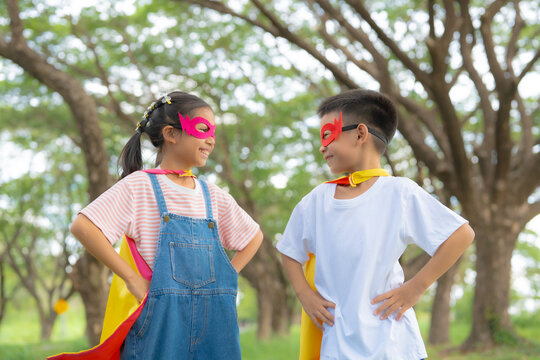 Happy Children in Superhero Costumes Looking at Each Other with Hero Poses, Celebrating Friendship, Teamwork, Confidence, and Imaginative Childhood Outdoors.