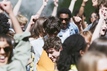 Fototapeta premium Group of young people dancing at an outdoor music festival with arms raised and hazy sunlight for concert and summer event marketing