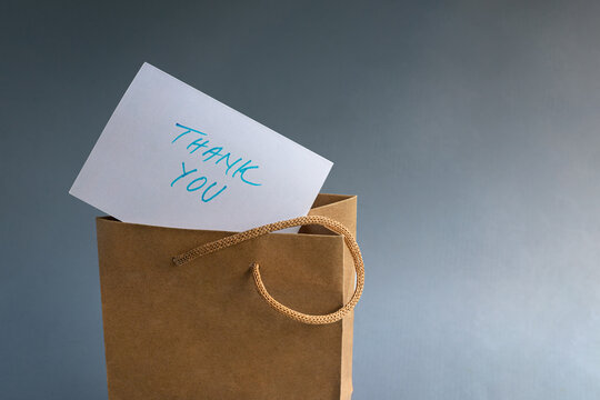 Thank you card with a brown paper gift bag. Isolated on blue background.