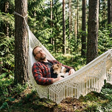 Man and dog relaxing in hammock in serene forest