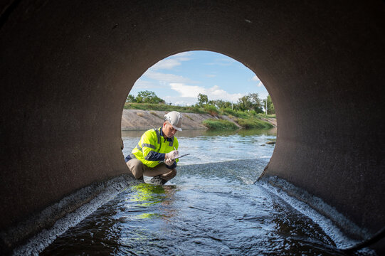 A specialist inspector is examining the drainage system of a large factory.