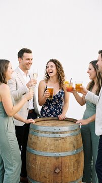 Friends celebrating with drinks around a wine barrel at an outdoor gathering