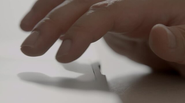 A close-up of a person's hand using a laptop trackpad with fingers touching the surface in a bright minimal workspace.