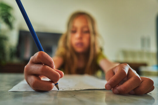Boy writing with a blue pencil - focus on hands