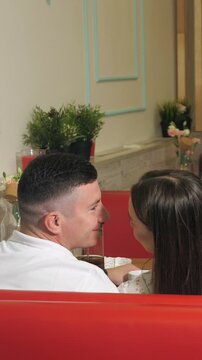 Beautiful young couple on a romantic date sitting in a cozy cafe, tenderly looking at each other, flirting, talking, and sharing an intimate kiss while enjoying their time together