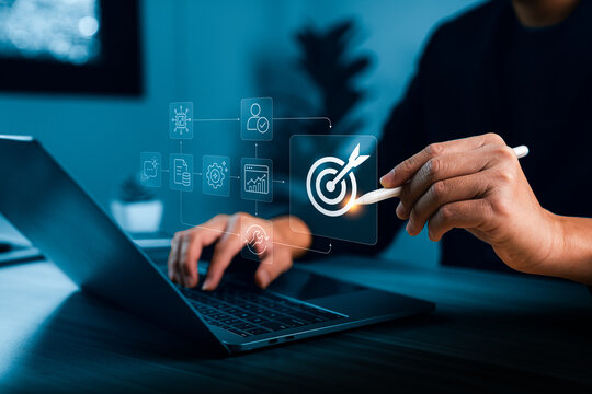 Business person using stylus and laptop with virtual AI workflow process icons showing automation steps data analysis user verification and target objective in modern digital workspace