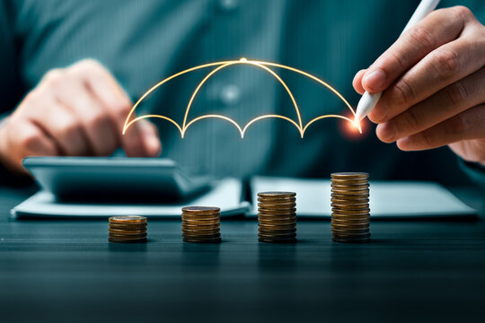 Financial risk protection concept with business hand drawing umbrella over growing coin stacks showing investment safety wealth security and risk management planning strategy
