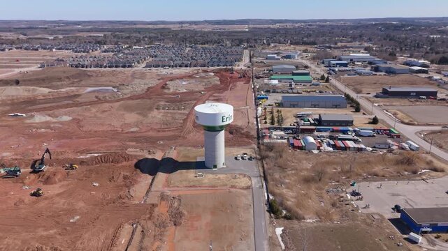 Striking aerial drone video of Erin, Ontario reveals large-scale housing development, earth movers, water tower, and suburban sprawl under clear daylight, highlighting growth and expansion.