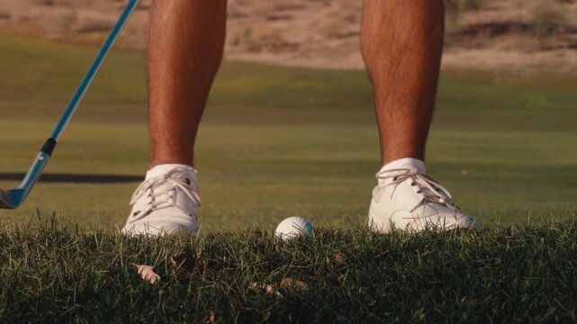 golfer hits ball and makes huge divot in the rough, close up extreme slow motion golf shot from the side with dirt flying on sunny day in 4k 800 fps