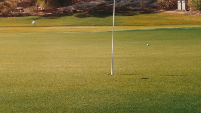 Golf shot landing close to green with lots of backspin, perfect approach shot next to hole,