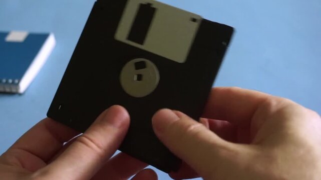 Person's hands holding and showing old floppy disks, a vintage data storage medium from the 90s