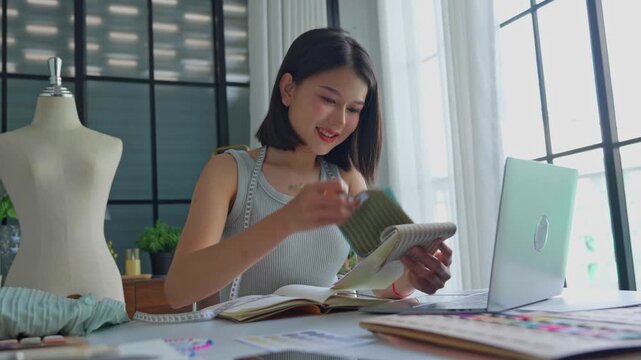 Asian woman tailor talking note when talking with customer on laptop