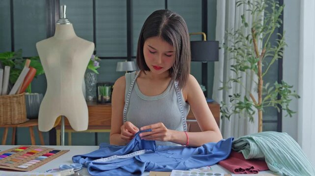 Asian woman tailor using sewing pins with cloth on table