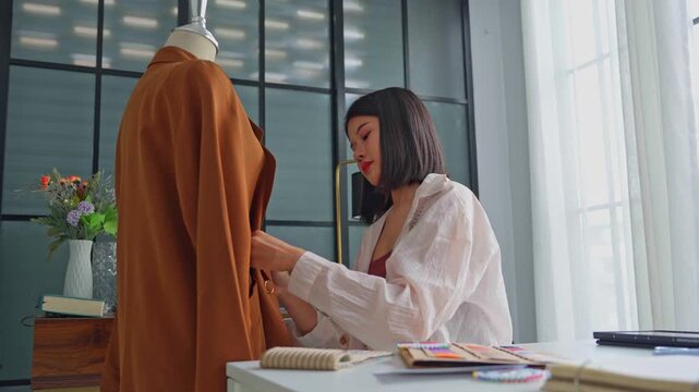 Asian woman designer using fabric pins with cloth on clothing try-on stock