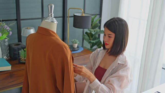 Asian woman designer using fabric pins with cloth on clothing try-on stock