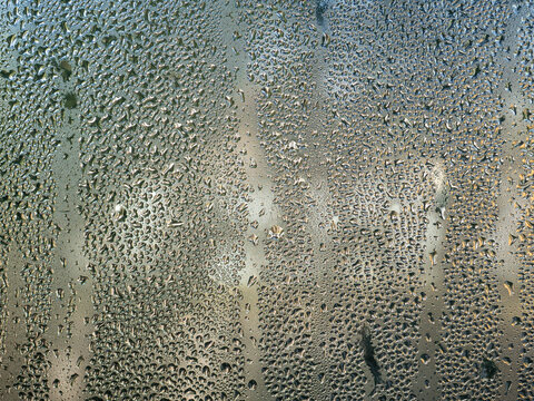 Abstract shiny dark background, texture. Water drops on glass. Wet, fogged glass, close-up.