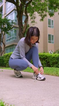 Asian sport woman tying sneaker lance in park
