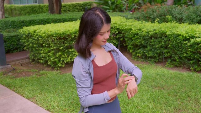 Asian sport woman checking heart rate on smartwatch in park