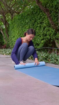 Asian woman rolled up yoga mat