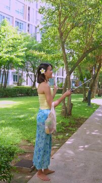 Asian woman in swimsuit using selfie stick hold smartphone live streaming on social platform in park