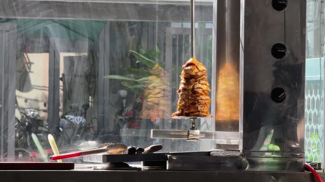 Doner Chicken Kebab Rotating on Vertical Spit Behind Glass on the street