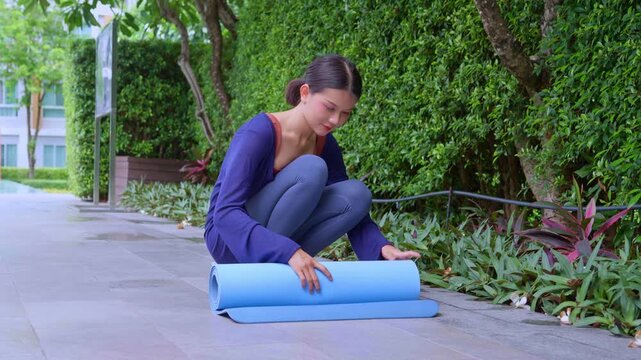 Asian woman rolled up yoga mat