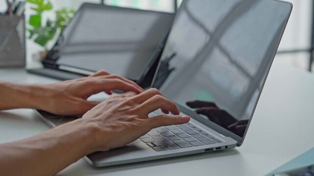 Asian businessman typing on laptop with tablet on table