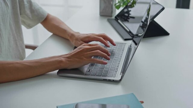 Asian businessman typing on laptop with tablet on table