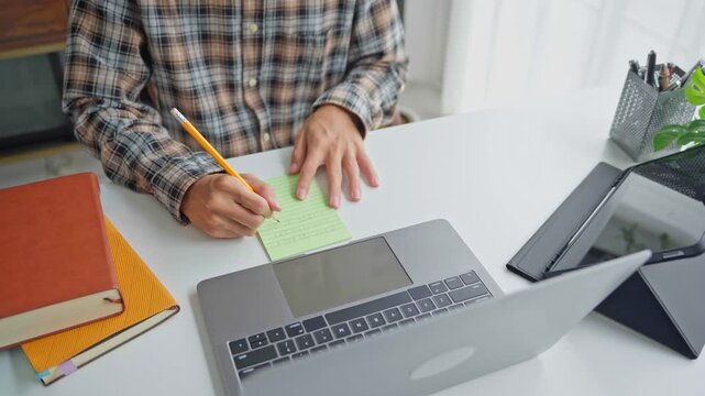 Asian businessman taking note during vdo conferrance on laptop