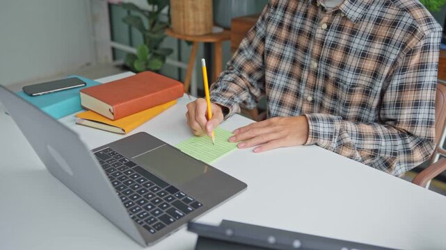 Asian businessman taking note during vdo conferrance on laptop