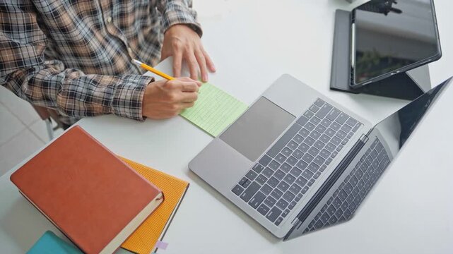 Asian businessman taking note during vdo conferrance on laptop