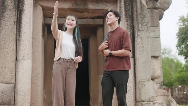 A female tour guide is introducing and providing information to a male tourist while they are walking through the historical site.