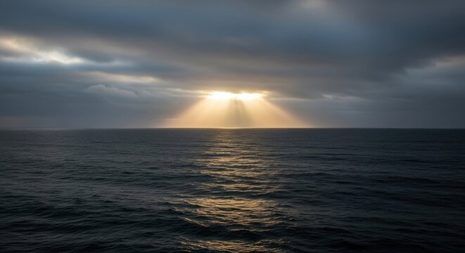 Dramatic sunset over the ocean with sun rays breaking through dark clouds