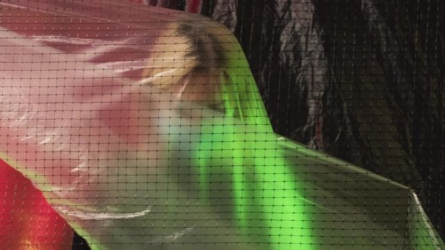 Allergy hurting. Ecology problem. Conceptual art. Lady in medicine mask being covered by transparent polyethylene film red green background copy space.