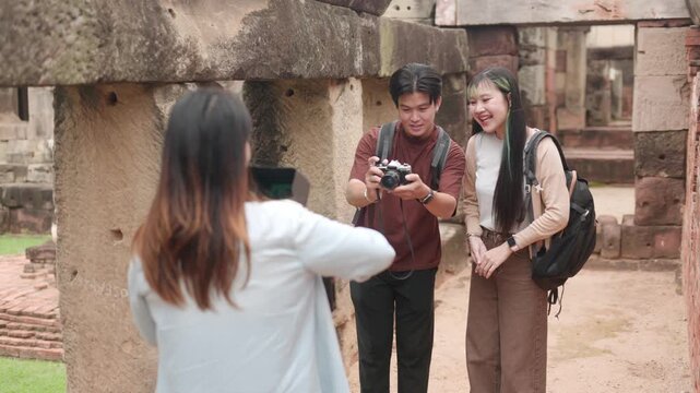 While filming a documentary, travelers examine a map on a tablet at the ruins of an ancient site.