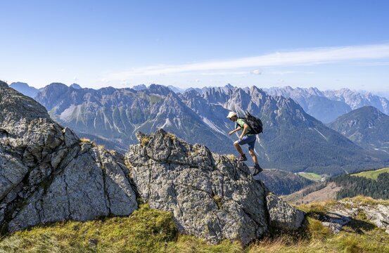 Mountaineer on a rocky ridge in front of a mountain panorama, view of the mountain peaks of Cresta Righile and Cresta del Ferro in South Tyrol, Carnic High Mountain Trail, Carnic Main Ridge, Carnic Alps, Carinthia, Austria